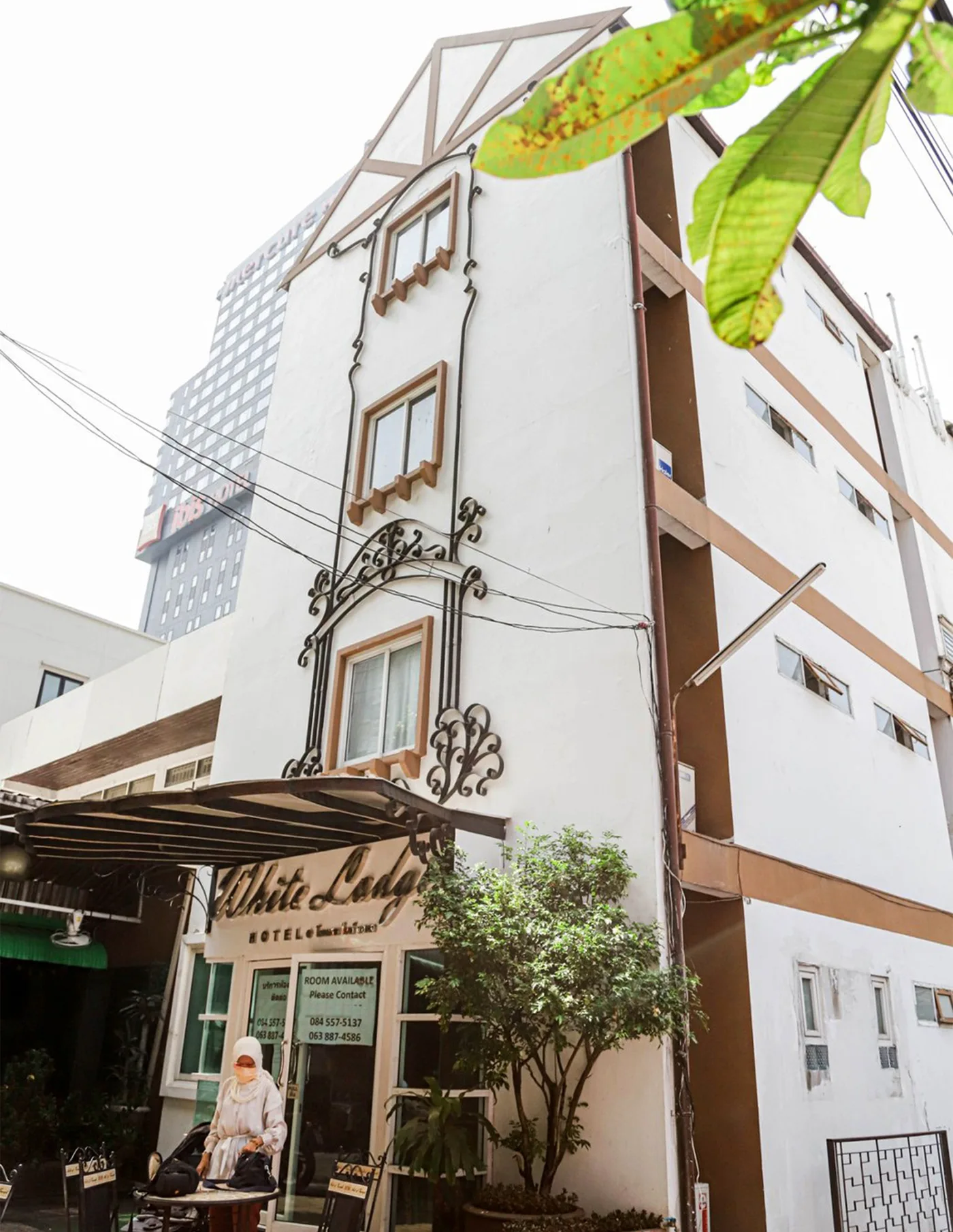 The White Lodge Hotel — a slender white boutique building with arched windows and a little streetside cafe, near Siam